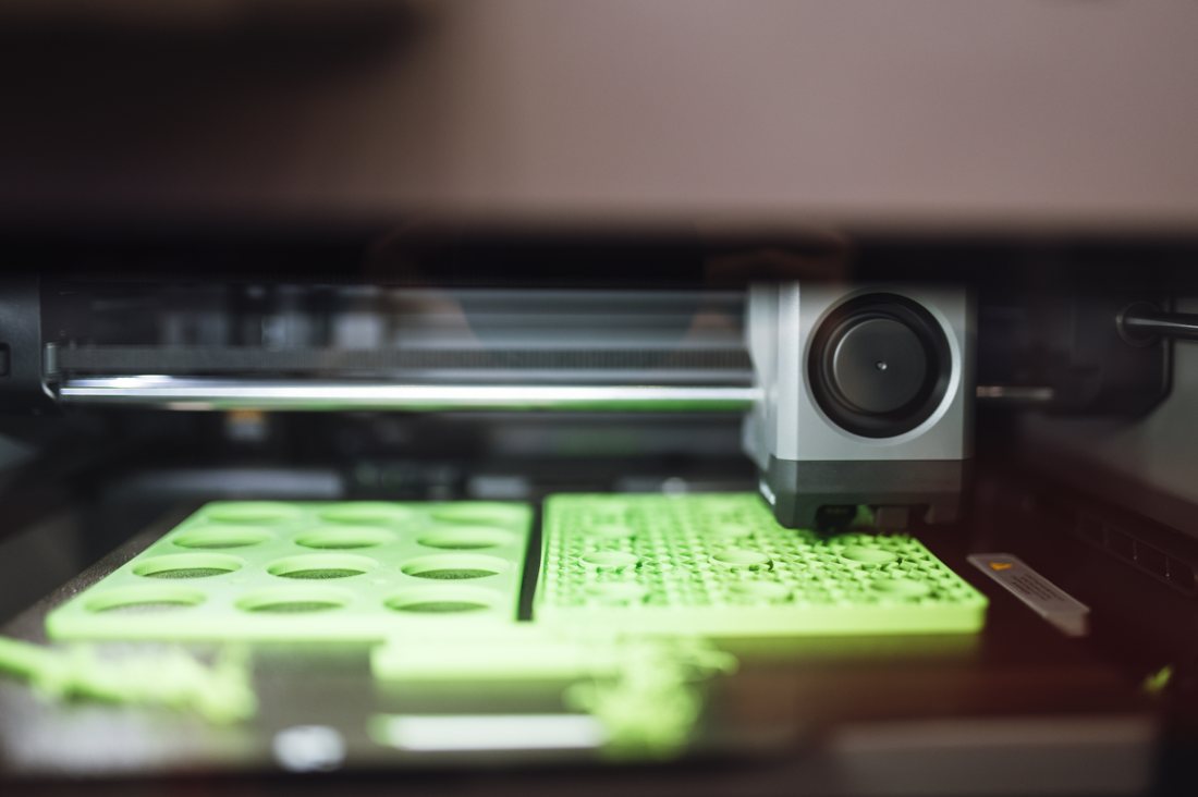 Impresora 3D produciendo piezas verdes